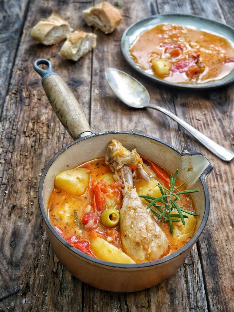 Une casserole en fonte avec un ragout de pommes de terre tomates olives et poulet