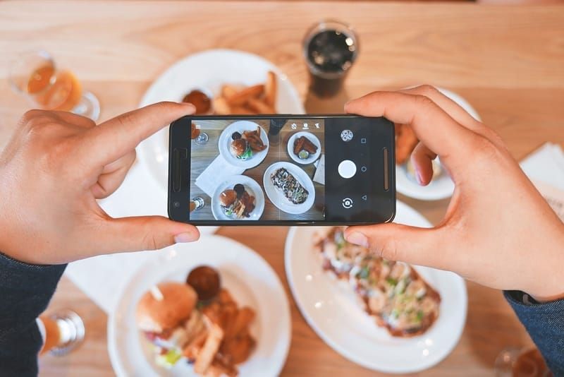 Un smartphone en train de photographier une scène culinaire